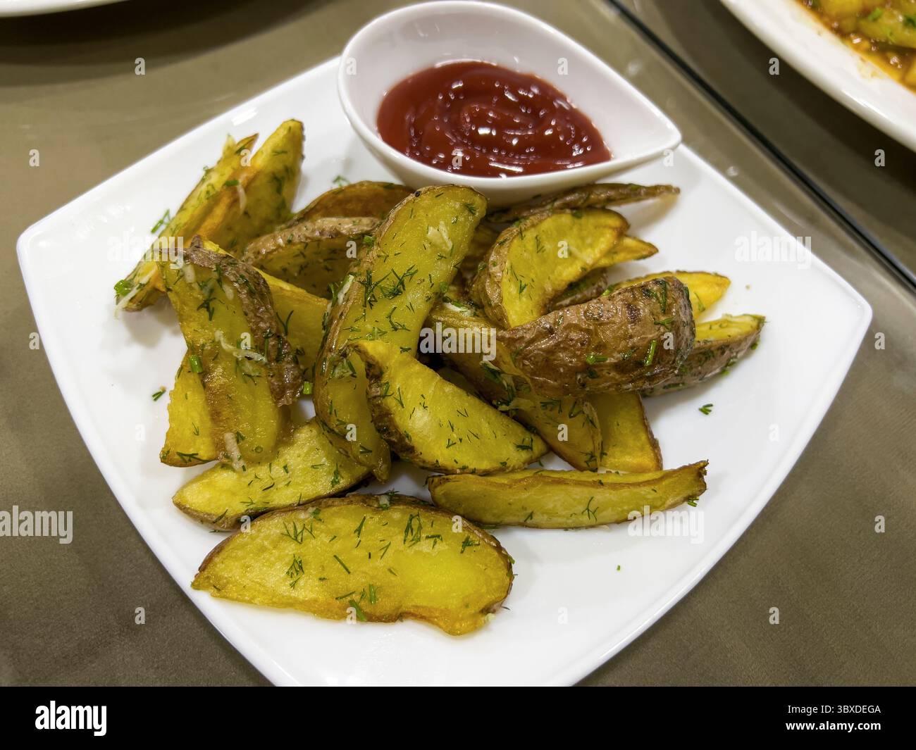 Die Kartoffeln werden gebraten und mit Ketchup gedünstet. Stockfoto