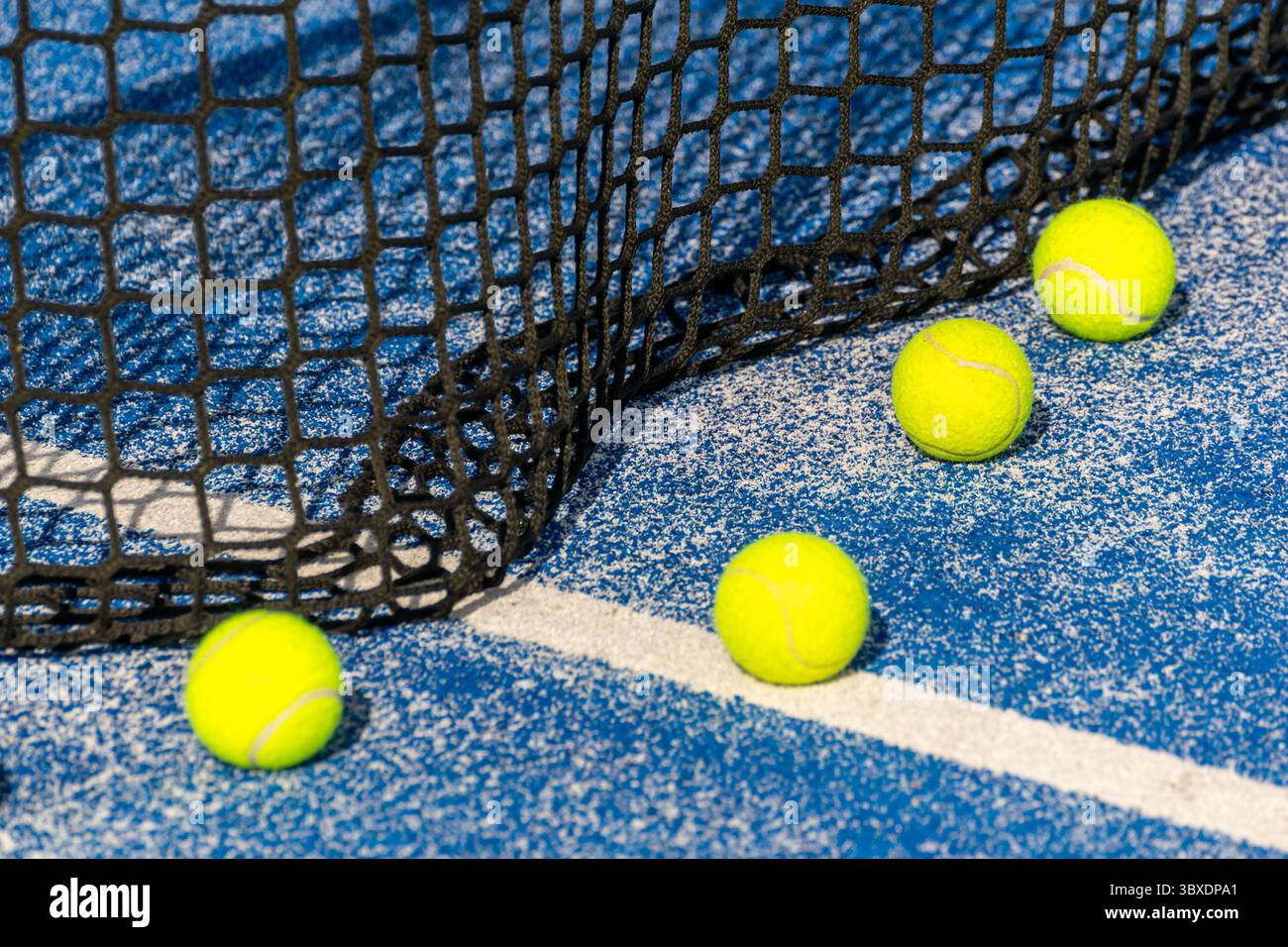 Mehrere gelbe Padel-Bälle auf einem leeren Court Padel-Bälle auf einem blauen Hof in der Nähe der Weißen Linie Stockfoto