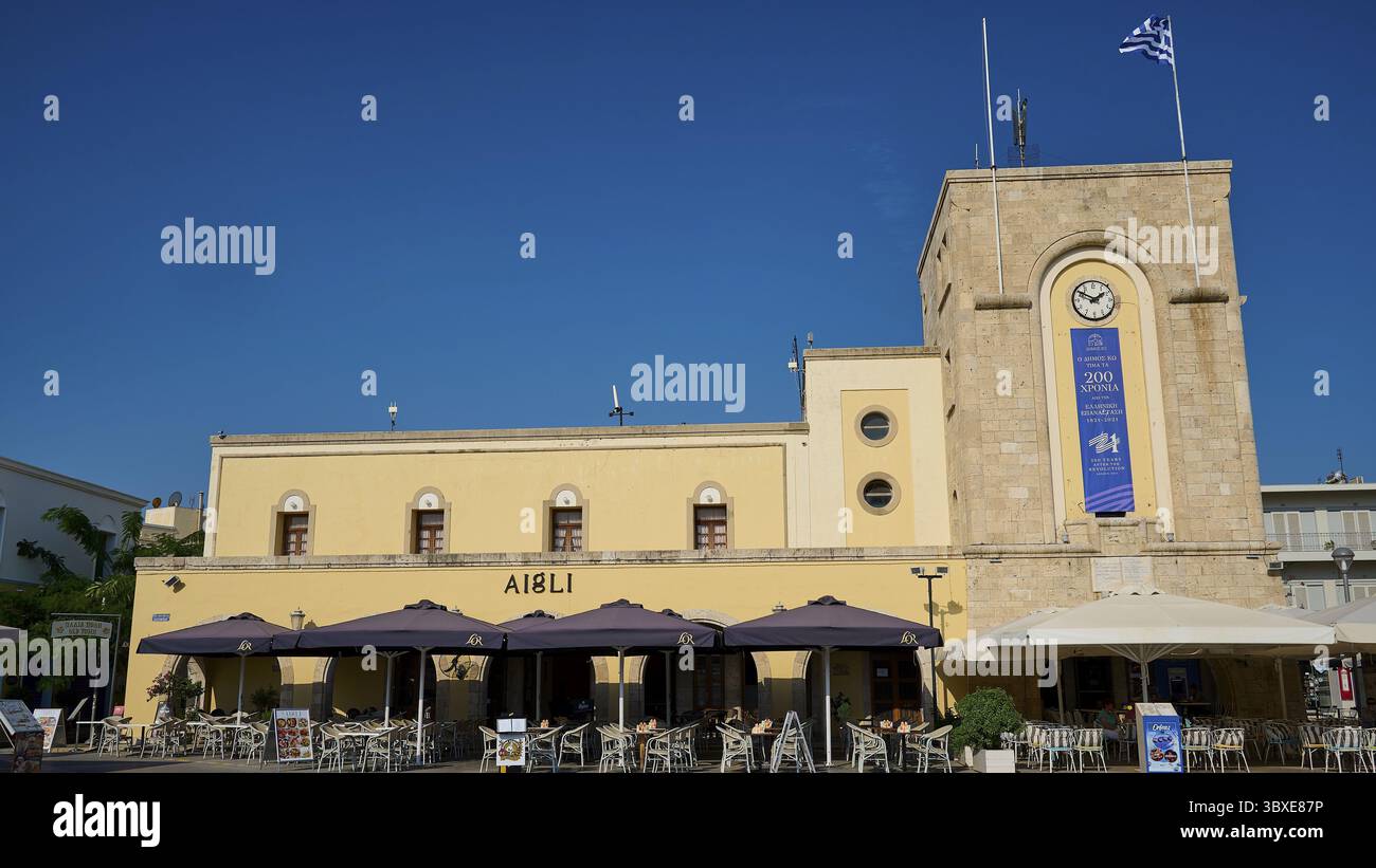 Kino, Eleftherias-Platz, historisches Gebäude mit Uhrenturm und Cafés unter blauem Himmel, Stadt Kos, Kos, Dodekanese, griechische Inseln, Griechenland Stockfoto