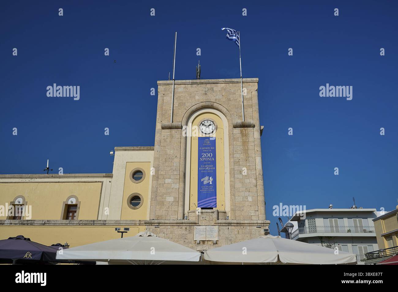 Kino, Eleftherias-Platz, historischer Uhrenturm mit griechischer Flagge vor klarem Himmel, Stadt Kos, Kos, Dodekanes, griechische Inseln, Griechenland Stockfoto