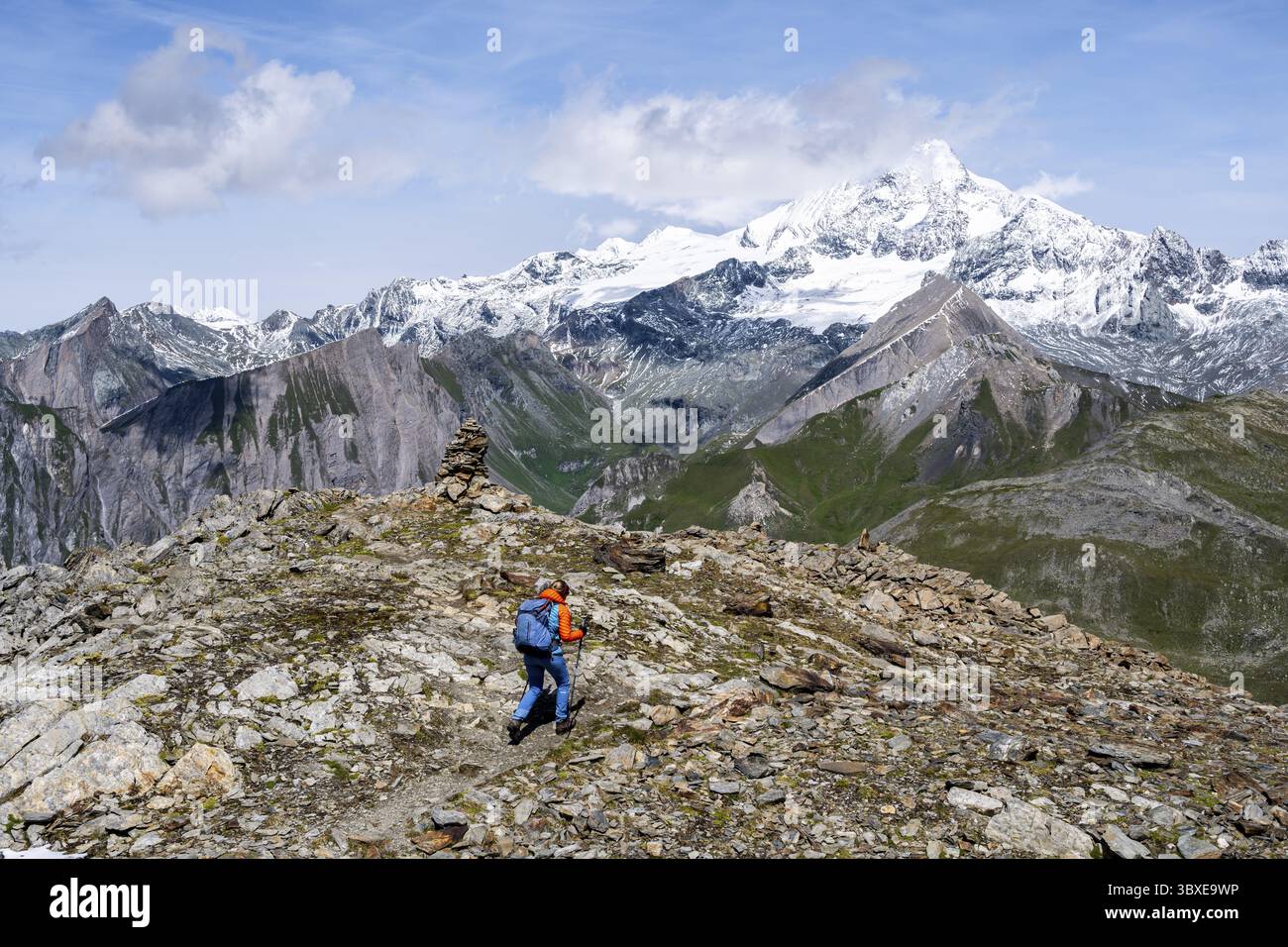 Bergsteiger auf einem Wanderweg, schneebedeckter und vergletschter Gipfel des Großglockners im Hintergrund, Wiener Hoehenweg, Schober-Gruppe, hohe Tauern Stockfoto