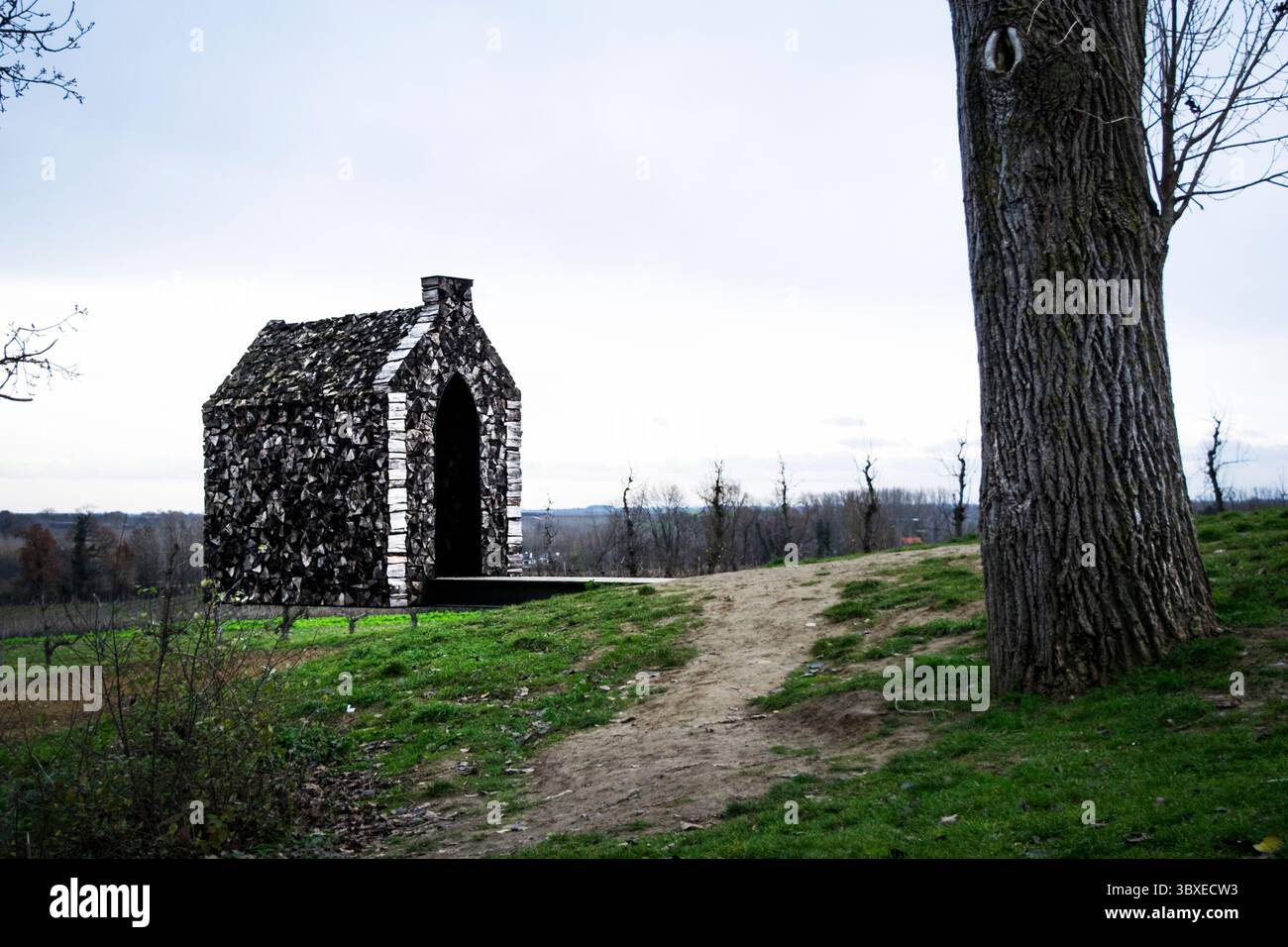 Entdecken Sie eine fesselnde Kunstinstallation, eine rustikale Kapelle in einer ruhigen natürlichen Umgebung. Dieses emotional resonante Bild weckt Frieden, Reflexion. Stockfoto