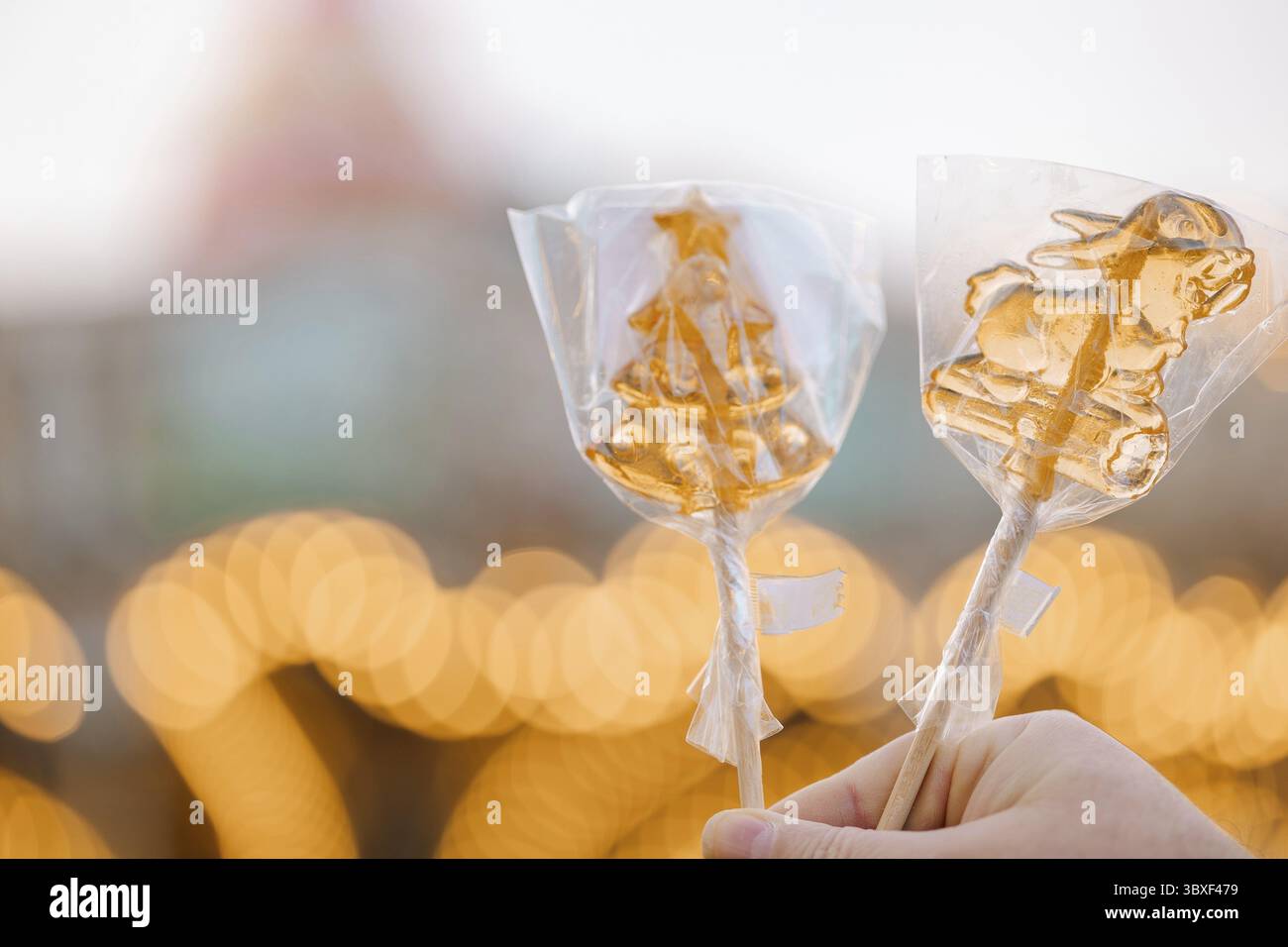 Hand hält goldene Weihnachtslutscher am Stock. Stockfoto