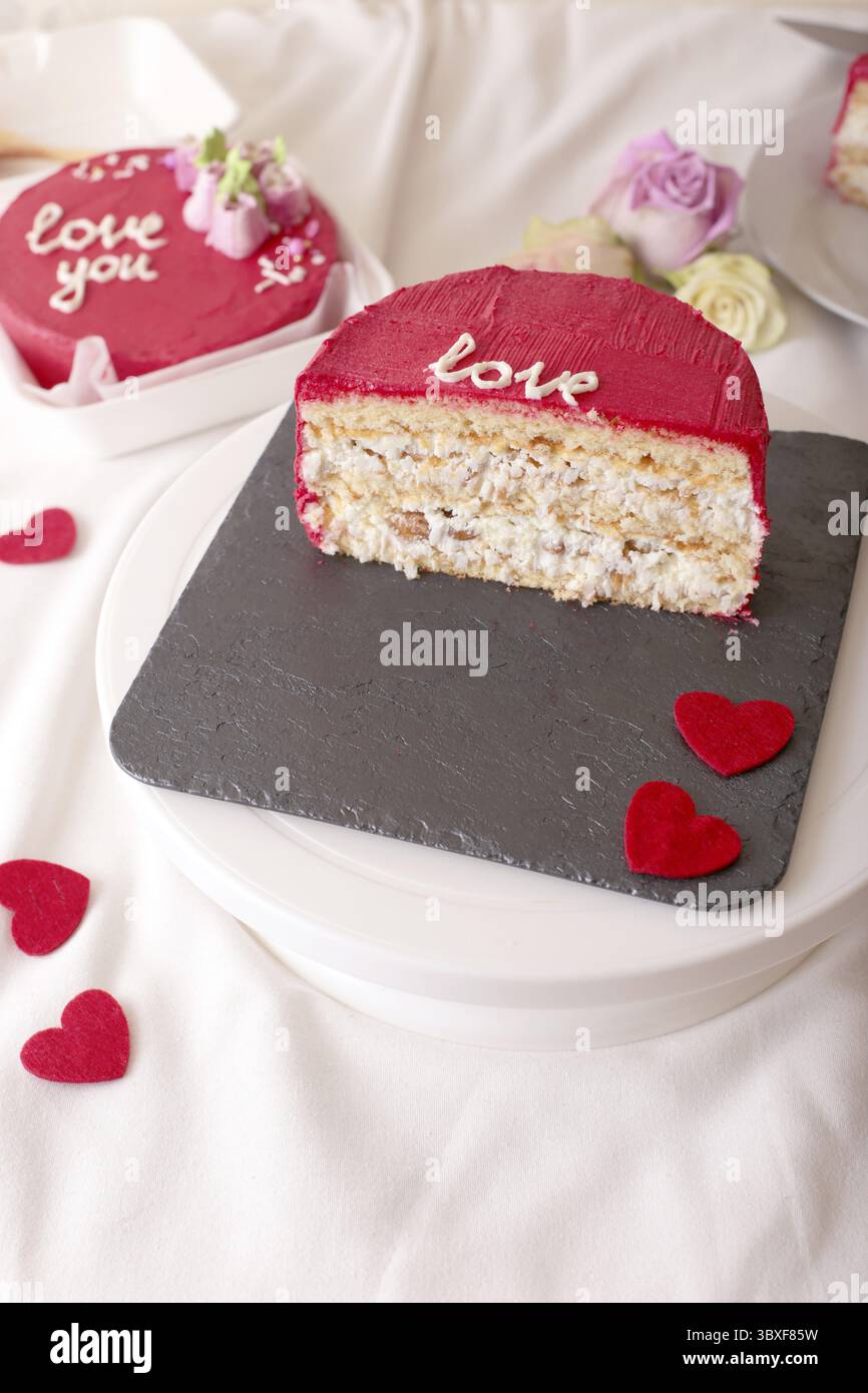 Rote valentinskuchenscheibe mit Herzdekoration auf Schieferplatte Stockfoto