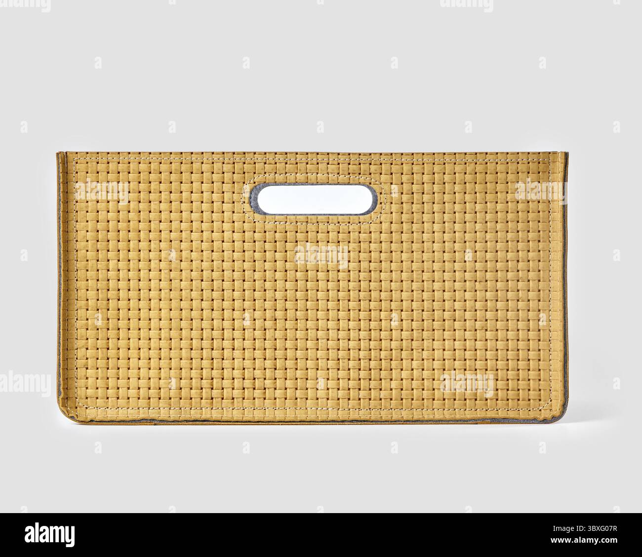 Nahaufnahme einer modischen Handtasche aus gelbem Leder mit gewebter Textur und einzigartigem Griff vor einem klaren weißen Hintergrund Stockfoto