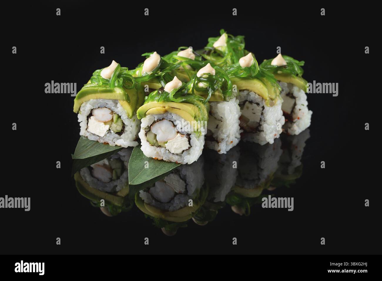 Traditionelle, köstliche, frische Sushi-Rolle auf schwarzem Hintergrund mit Spiegelung. Sushi-Rolle mit Reis, Nori, Frischkäse, Tobiko-Kaviar, Avocado. So Stockfoto