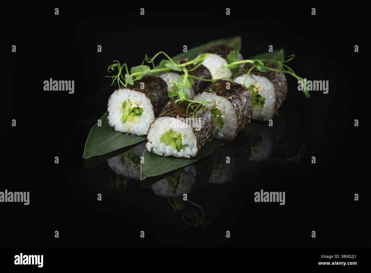 Traditionelle, köstliche, frische Sushi-Rolle auf schwarzem Hintergrund mit Spiegelung. Sushi-Rolle mit Reis, Nori, Frischkäse, Tobiko-Kaviar, Avocado. So Stockfoto