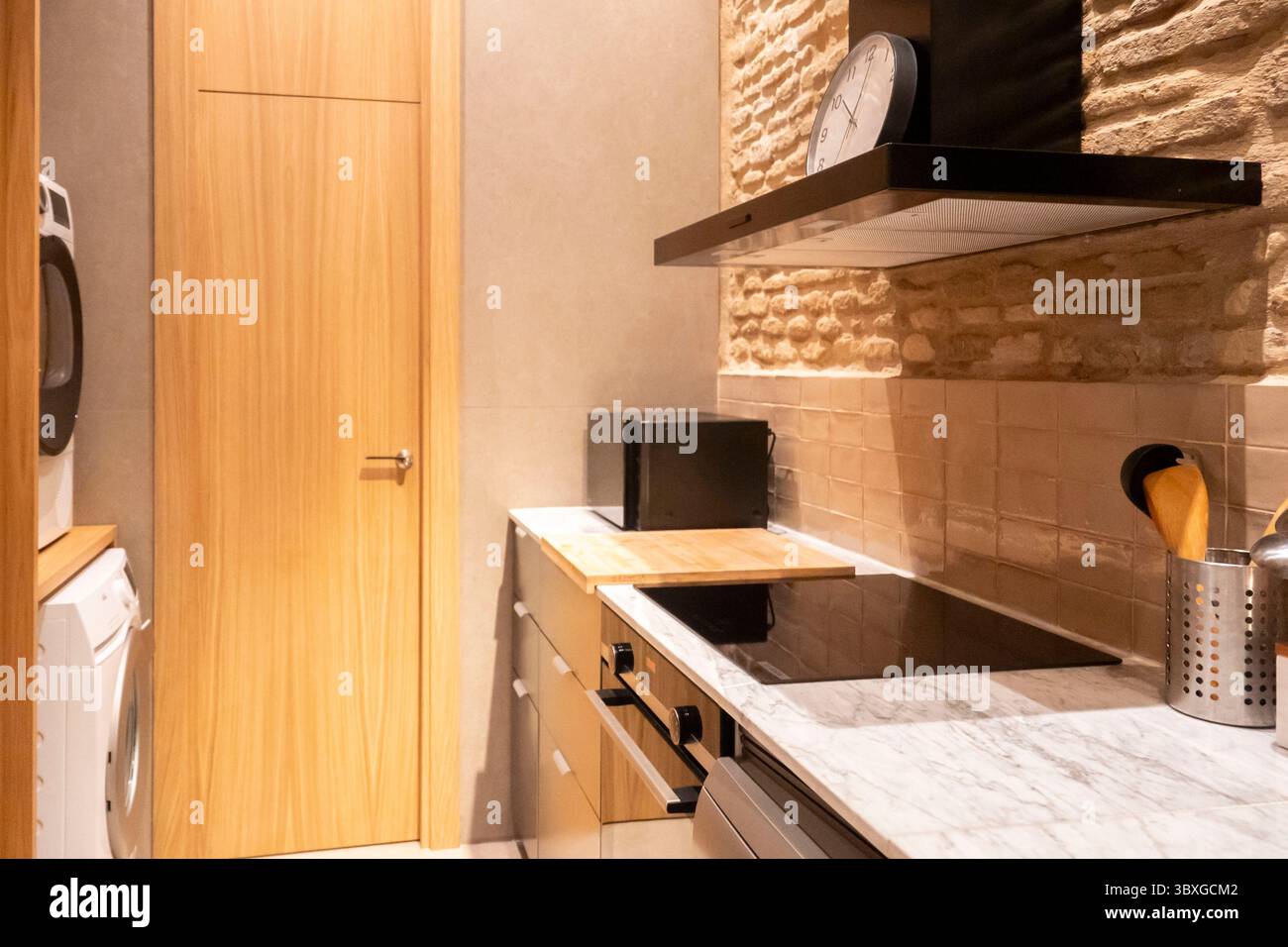 Die Küche verfügt über einen Ofen mit Herd, eine Mikrowelle für schnelle Mahlzeiten und eine Waschmaschine, um Waschaufgaben bequem zu erledigen Stockfoto