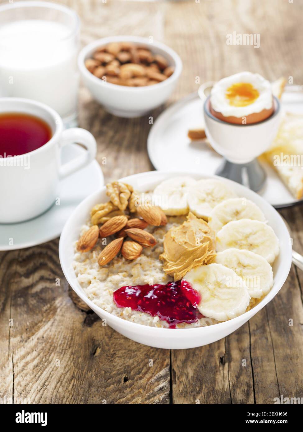 Haferflocken mit Nüssen und Marmelade, weich gekochte Eier, selektiver Fokus, Seitenansicht, vertikaler Rahmen Stockfoto