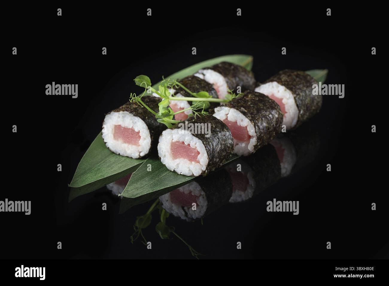 Traditionelle, köstliche, frische Sushi-Rolle auf schwarzem Hintergrund mit Spiegelung. Sushi-Rolle mit Reis, Nori, Frischkäse, Tobiko-Kaviar, Avocado. So Stockfoto