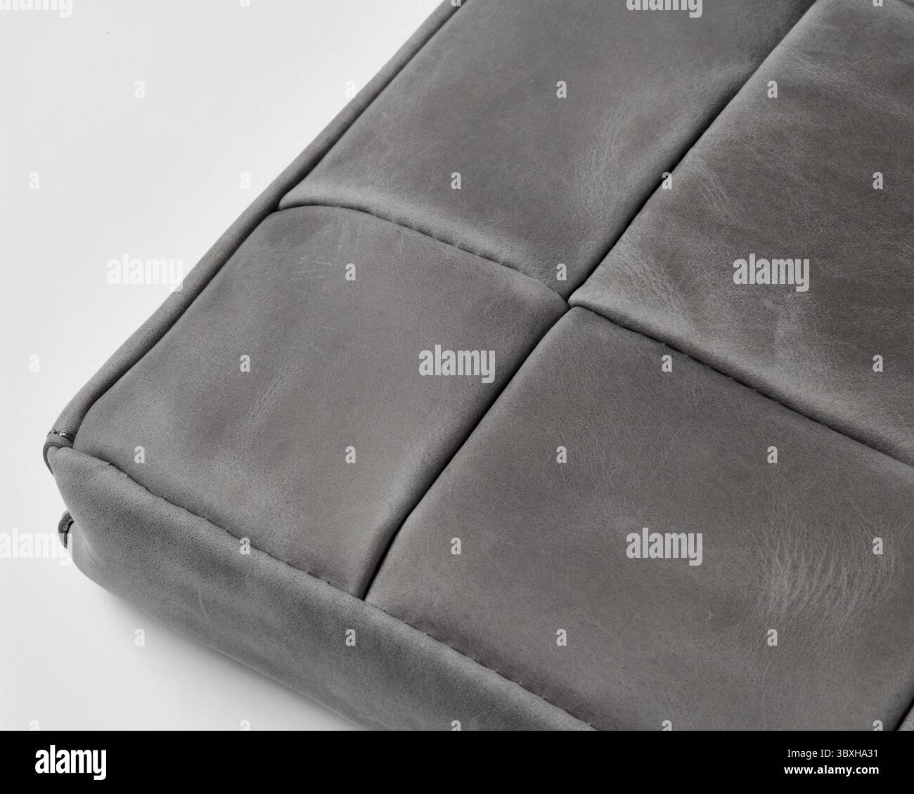 Graue Lederoberfläche mit sichtbaren Nähten und Texturen, die auf hochwertige Handwerkskunst hinweisen Stockfoto