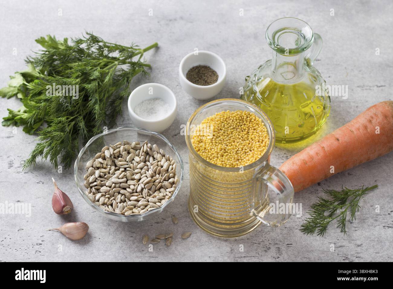 Lebensmittel, Zutaten für vegane Schnitzel: Hirse, Samen, Karotten, Kräuter, Knoblauch, Gewürze und Olivenöl auf grauem, strukturiertem Hintergrund Stockfoto