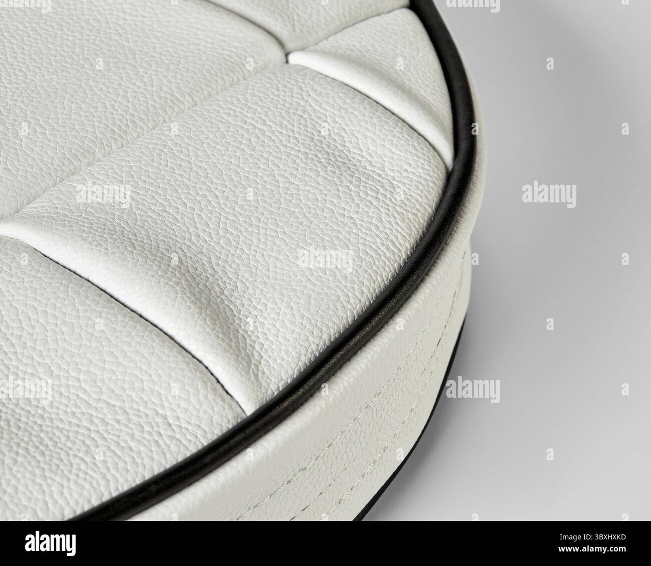 Nahaufnahme von weißen Lederpolstern mit schwarzen Paspeln, die die Textur und Handwerkskunst hochwertiger Möbel hervorheben Stockfoto