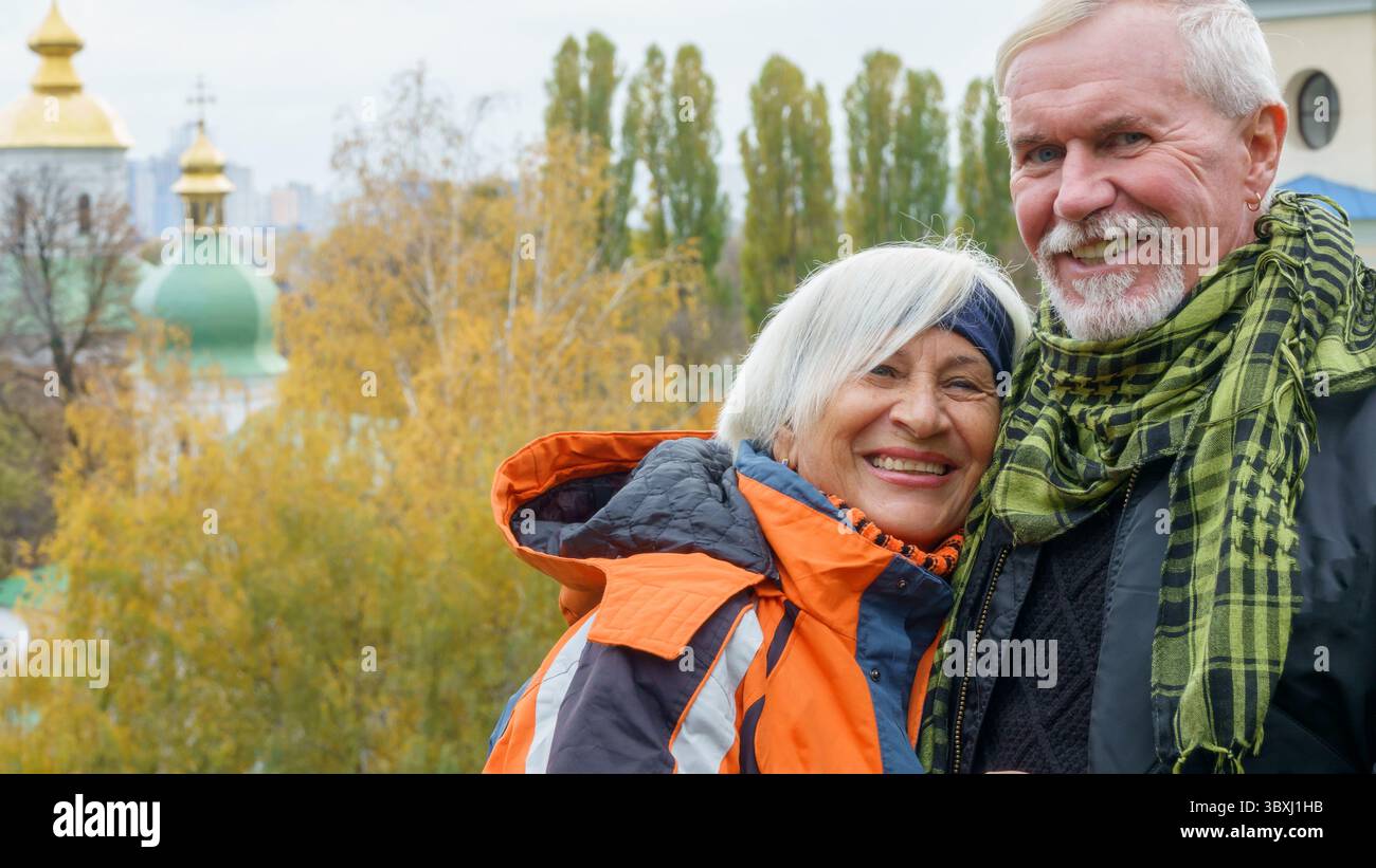 Fröhliches positives älteres Ehepaar vor dem Hintergrund gelber Herbstbäume in hellen Kleidern Stockfoto