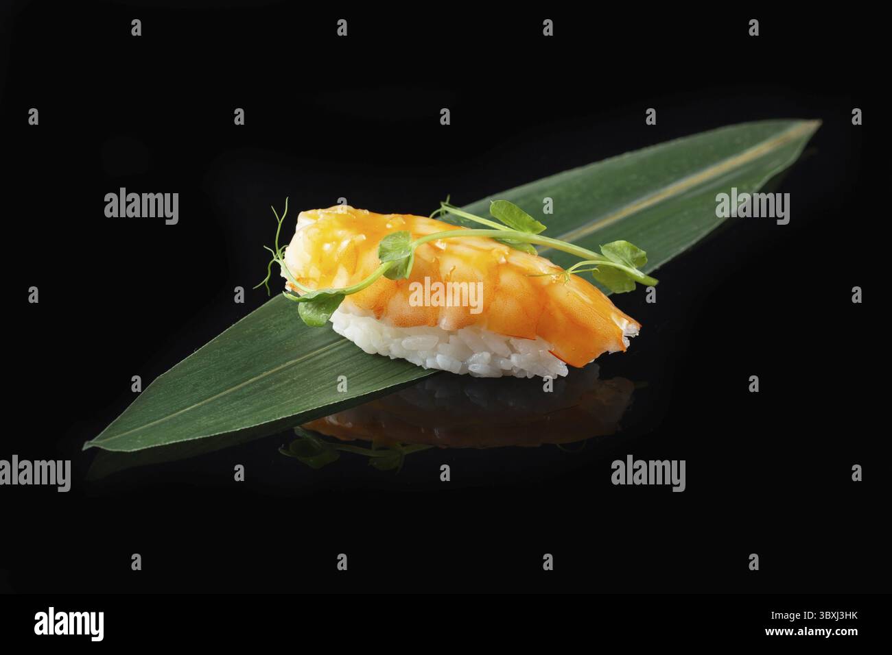 Traditionelle, köstliche, frische Sushi-Rolle auf schwarzem Hintergrund mit Spiegelung. Sushi-Rolle mit Reis, Nori, Frischkäse, Tobiko-Kaviar, Avocado. So Stockfoto