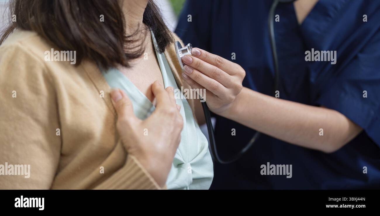 Eine Pflegekraft hört einem älteren Patienten mit einem Stethoskop aufmerksam zu und unterstreicht die Bedeutung einer gründlichen Gesundheitsbeurteilung Stockfoto
