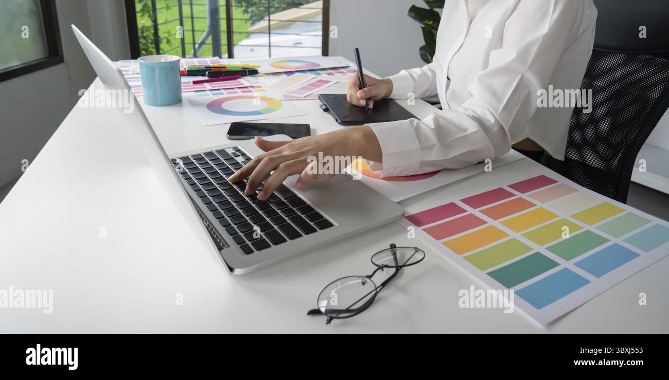 Kreativer Grafikdesigner, der mit Farbmustern und Design-Tools an Notebooks und Tablets arbeitet Stockfoto