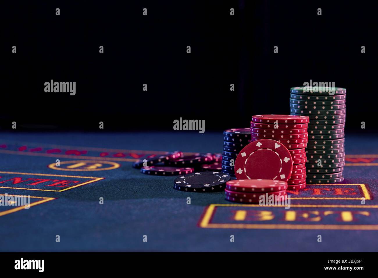 Bunte Stapel Chips auf einem blauen Abdeckung der Tabelle mit Markup stehen, einige von ihnen sind in der Nähe. Schwarzen Hintergrund. Spielen unterhalten Stockfoto