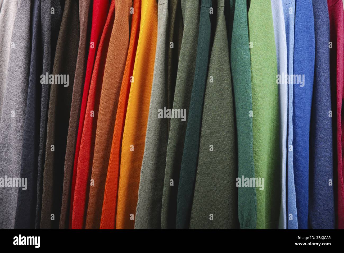 Warme Pullover. Herbst, Winterkleidung. Metallgestell mit verschiedenen Pullovern auf Kleiderbügeln in einer modernen Modeboutique. Leichtindustrie Stockfoto