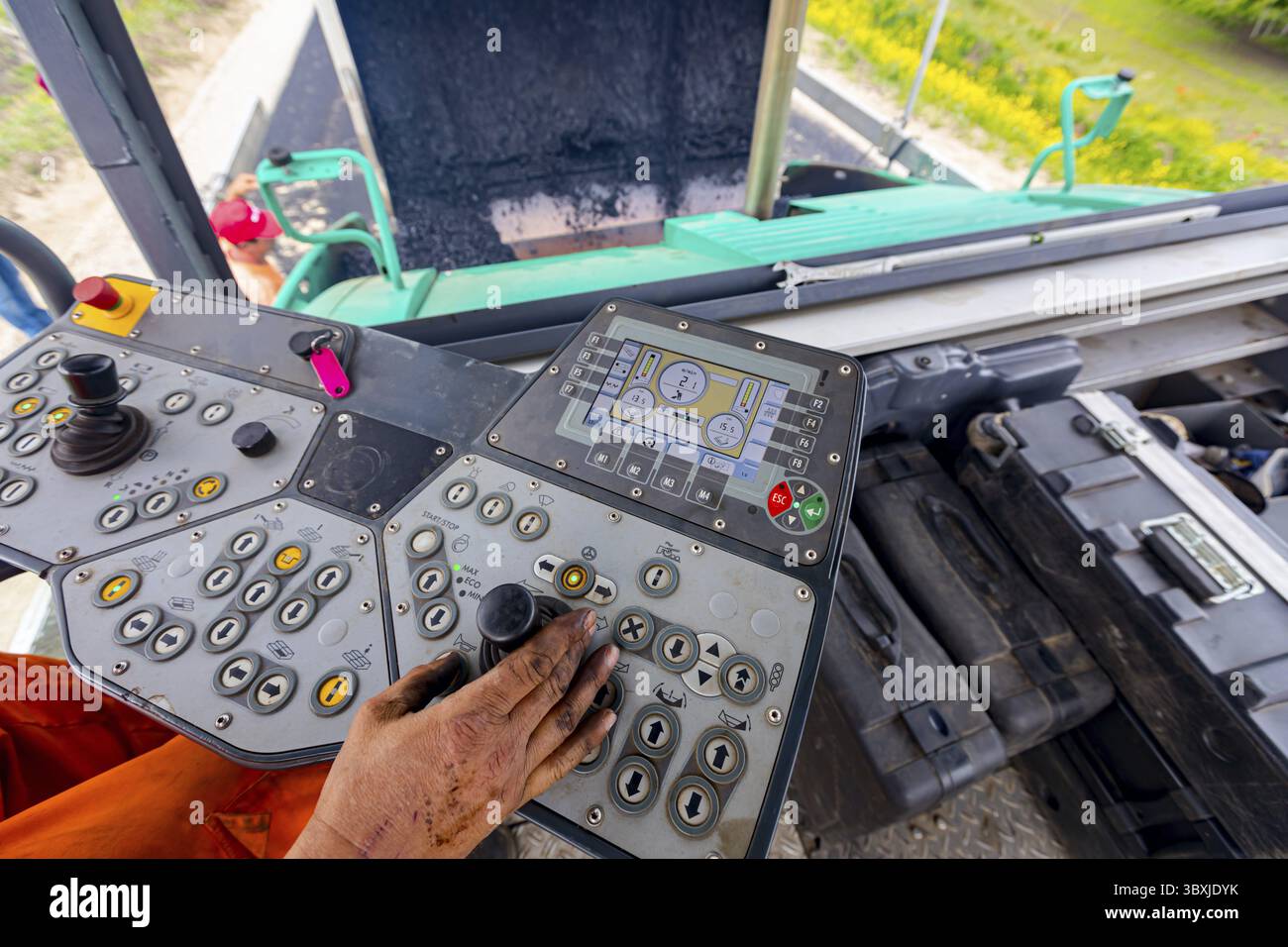 Arbeiter, Fahrer steuert Asphaltmaschine mit Lenker und Joystick Stockfoto