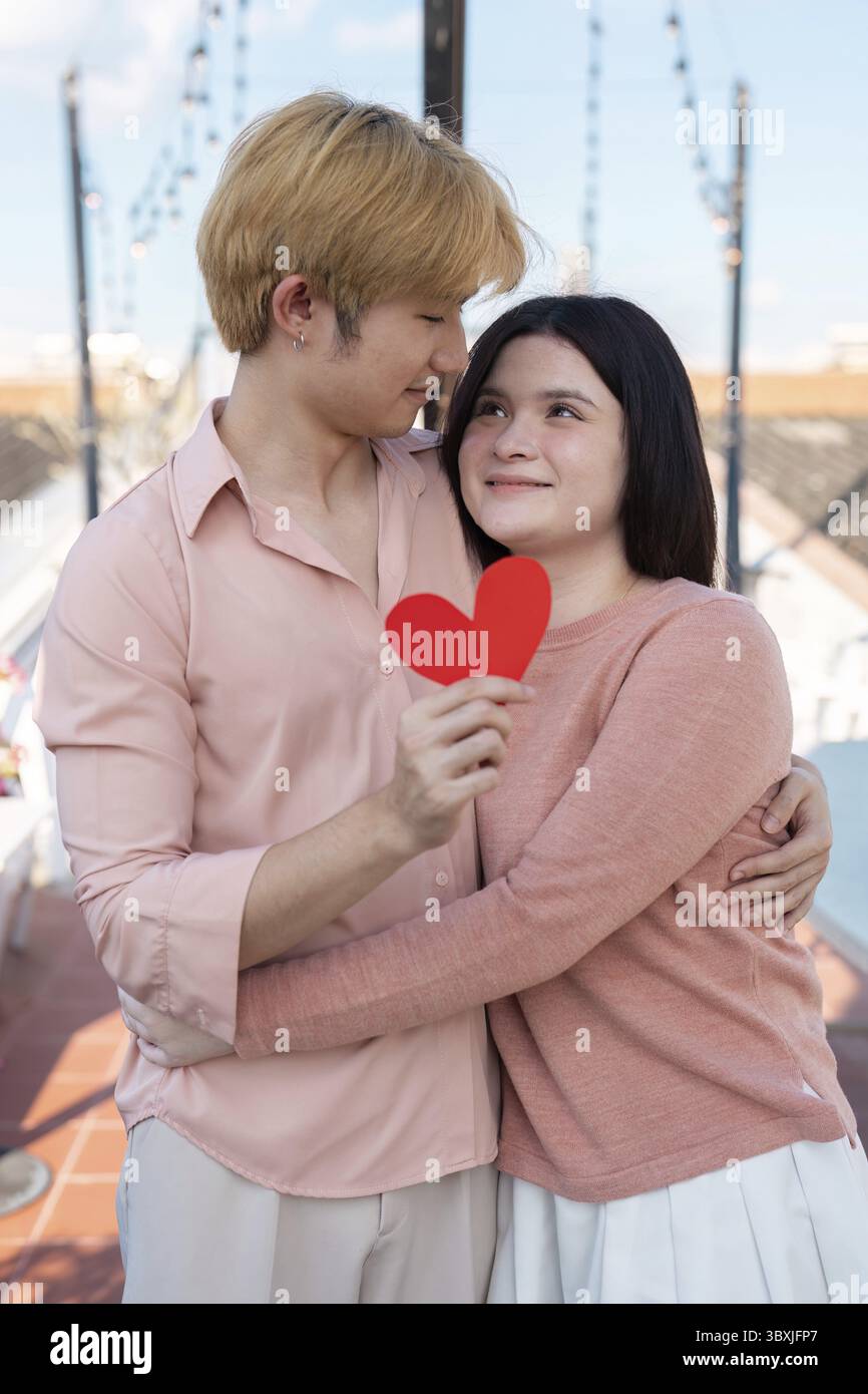 Ein Paar teilt einen intimen Moment am Valentinstag und genießt die atemberaubende Skyline, umgeben von Liebe und Stadtlichtern Stockfoto