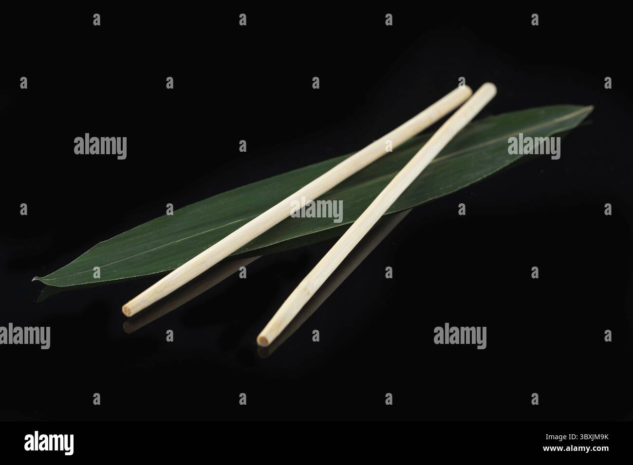 Sushi-Sticks auf einem Bananenblatt auf schwarzem Hintergrund mit Spiegelung. Sushi-Menü. Japanische Küche, Restaurant. Asiatische Küche Stockfoto