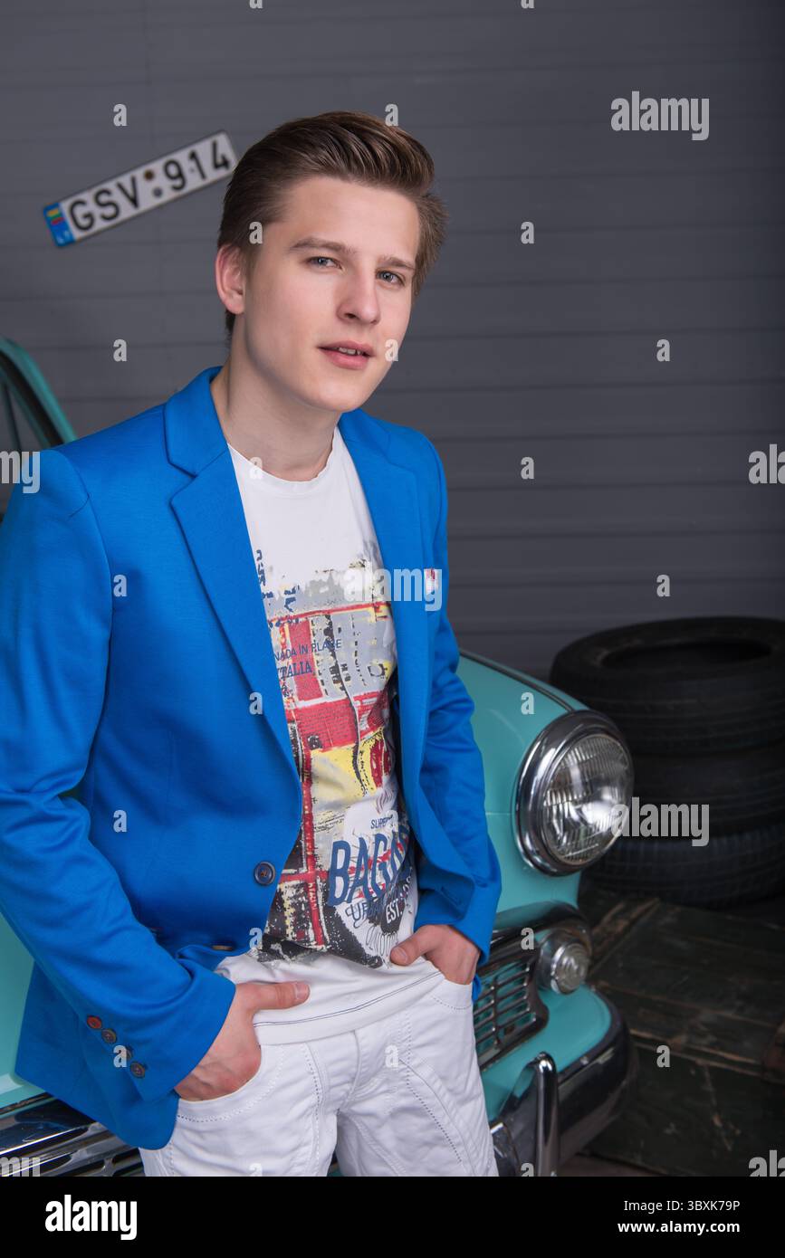 Porträt eines jungen Mannes in einer blauen Jacke in der Autogarage Stockfoto