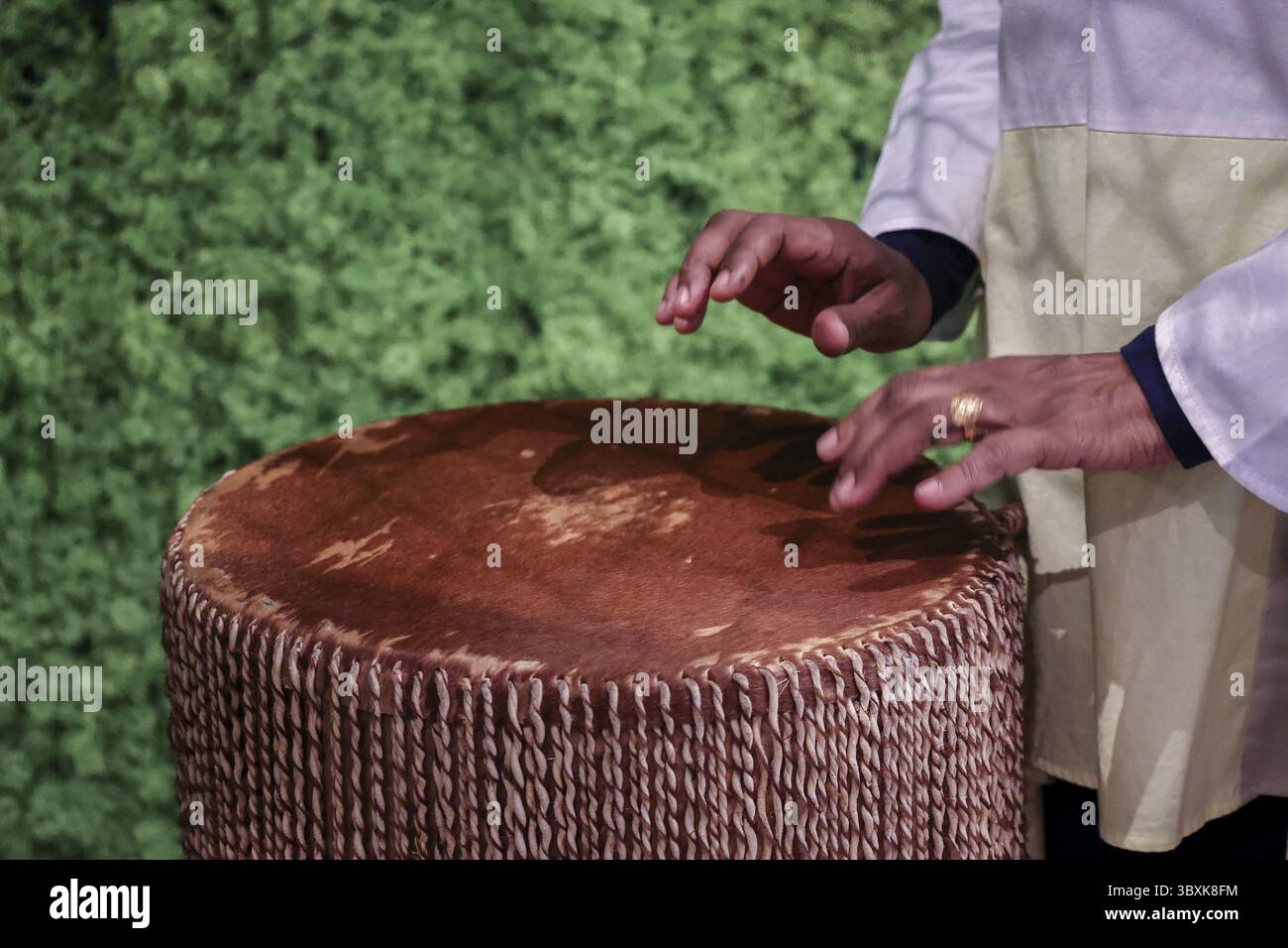 Afro-amerikanische Frau spielt afrikanische ethnische Schlagzeug. Schlagzeuger spielt afrikanische Musik auf Instrument Djembe. Nahaufnahme von Menschenhänden. Stockfoto