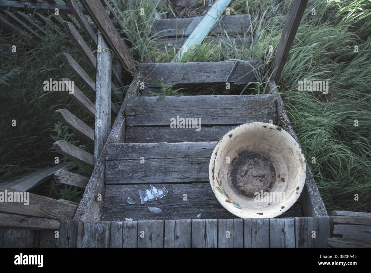 Alte hölzerne Veranda eines verlassenen Hauses, schmutziges emailliertes Waschbecken. Ansicht von oben Stockfoto