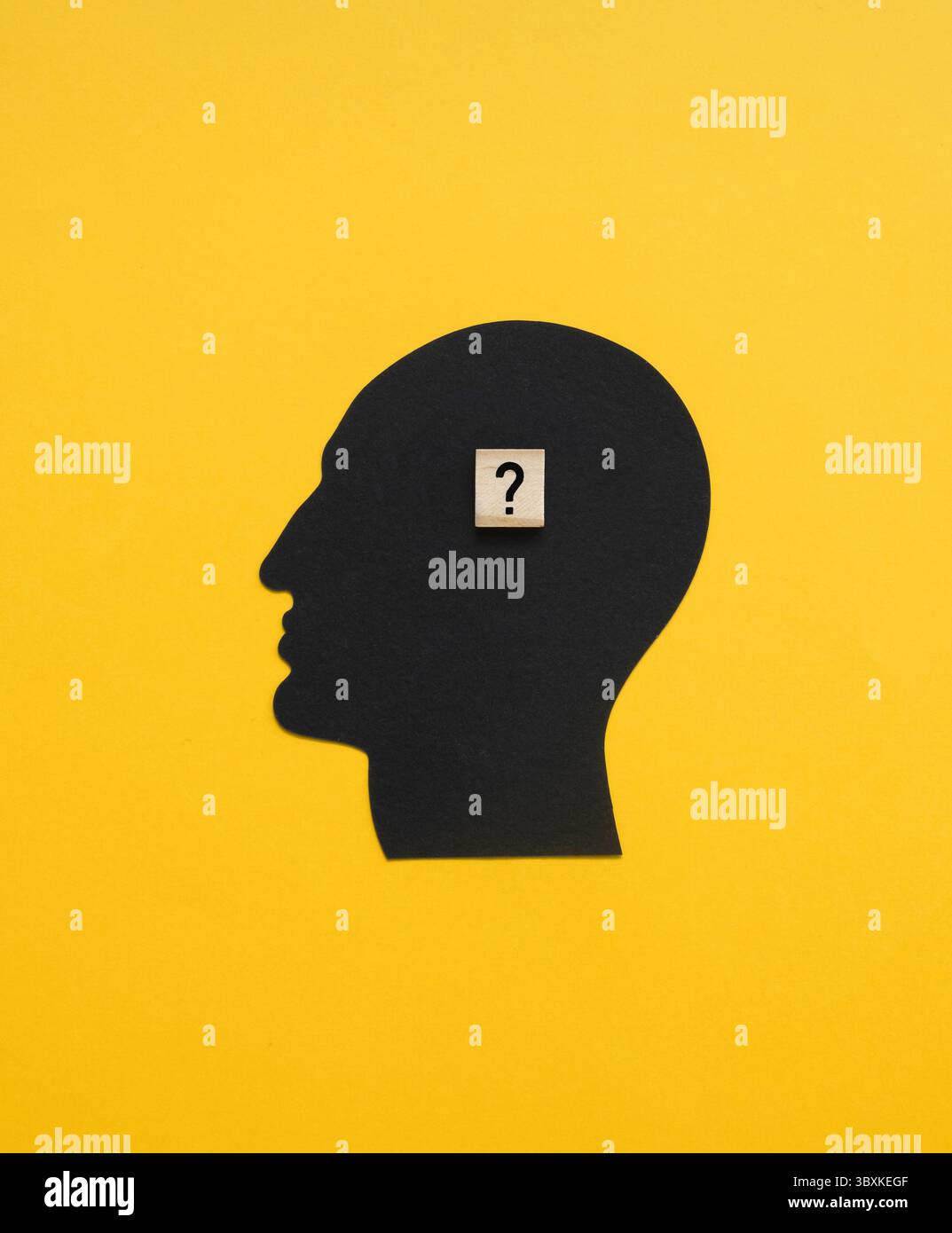 Symbol eines Pensigen Mannes, der eine Frage hat und auf eine Antwort wartet. Komposition mit schwarzem Menschenkopf und Holzblock mit schwarzem Fragezeichen. Stockfoto