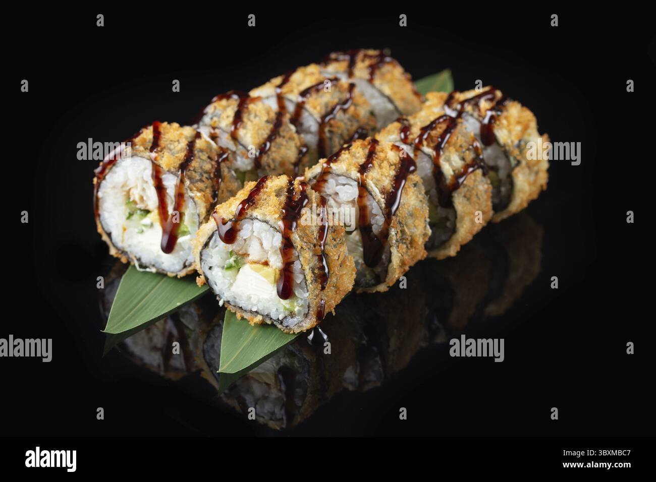 Traditionelle, köstliche, frische Sushi-Rolle auf schwarzem Hintergrund mit Spiegelung. Sushi-Rolle mit Reis, Nori, Frischkäse, Tobiko-Kaviar, Avocado. So Stockfoto