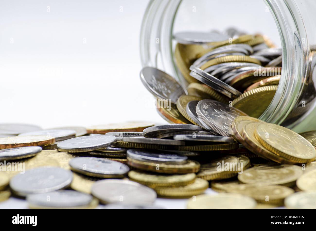 Goldmünzen in einem Glas mit weißem Hintergrund, das Geschäfts-, Investitions- oder Geldkonzept darstellt. Anpassbarer Platz für Text Stockfoto