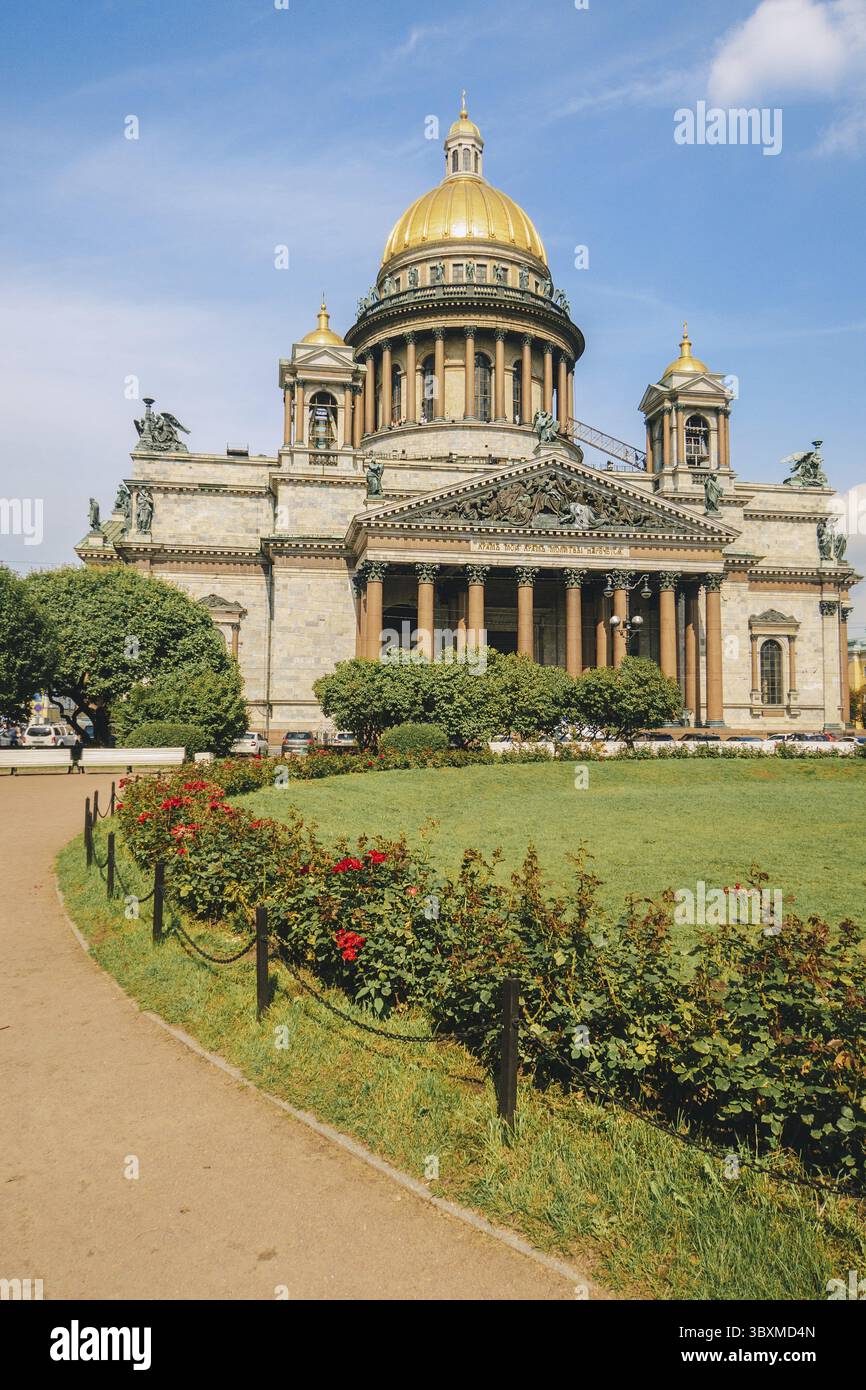Panoramablick auf die Isaakskathedrale. Isaakievskiy Sobor mit grünem Rasen und roten Rosen im Sommer, St. Petersburg, Russland. Vertikales Foto. Stockfoto