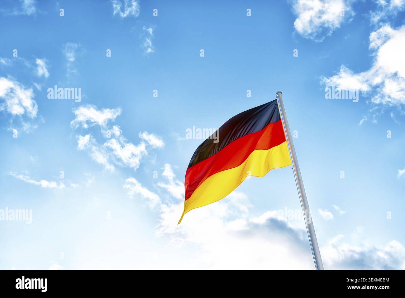 Eine deutsche Flagge mit schwarzen, roten und gelben Streifen vor Wolken in blauem Himmel Stockfoto