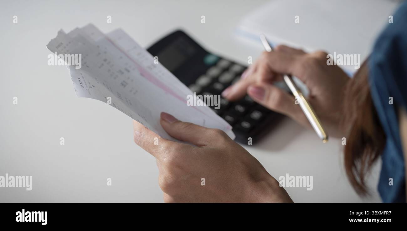 Der Schwerpunkt liegt auf der Verwaltung persönlicher Finanzen. Dabei prüft eine Person die Einnahmen sorgfältig und berechnet Ausgaben, um ihre Einsparungen zu steigern Stockfoto