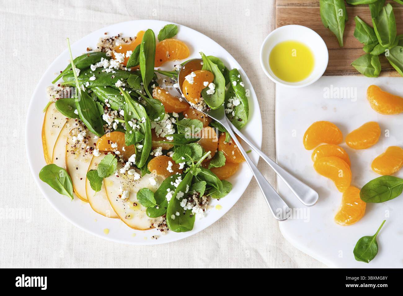 Salat aus Spinat und Quinoa mit Birnen, Orangen und Ricotta. Vorbereitung gesunder Mahlzeiten. Gerichte auf pflanzlicher Basis. Grünes Leben. Veganes Rezept. Styling von Lebensmitteln. Vegetarisch Stockfoto