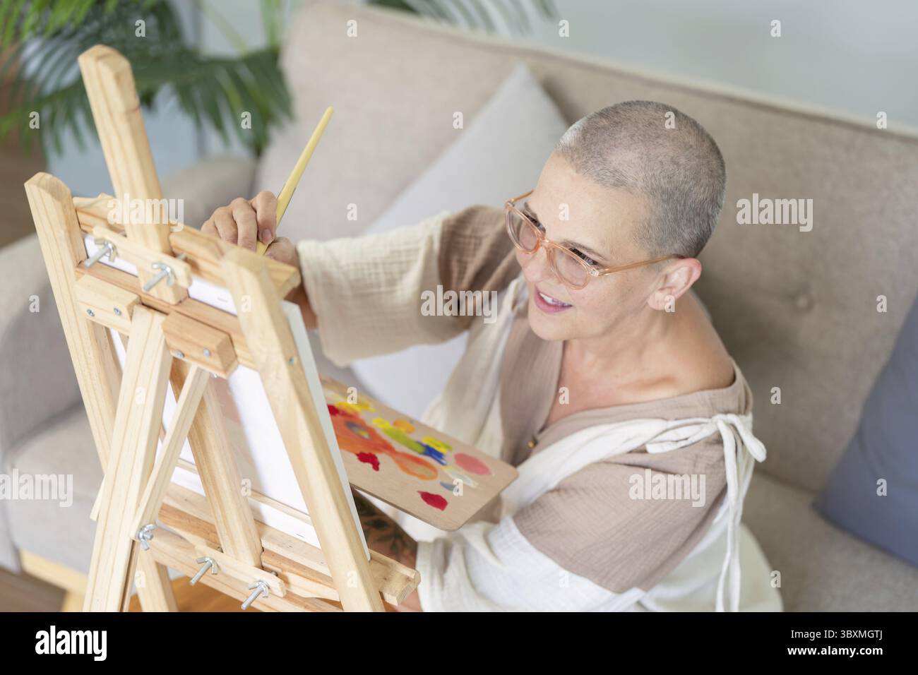 Seniorin, die sich auf die Schaffung eines Meisterwerks aus Leinwand konzentriert und die Hingabe und Liebe für die Kunst im späteren Leben repräsentiert Stockfoto