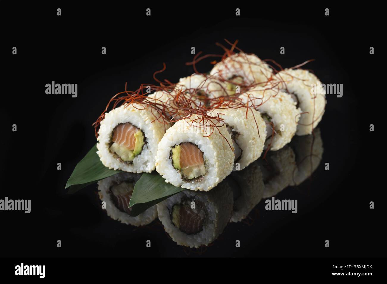 Traditionelle, köstliche, frische Sushi-Rolle auf schwarzem Hintergrund mit Spiegelung. Sushi-Rolle mit Reis, Nori, Frischkäse, Tobiko-Kaviar, Avocado. So Stockfoto