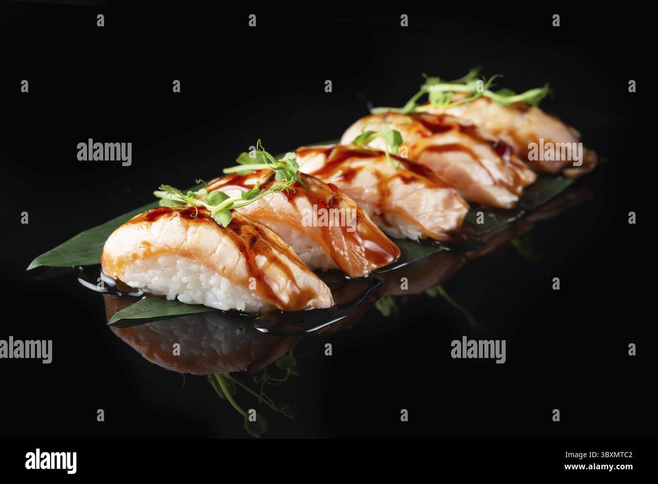 Traditionelle, köstliche, frische Sushi-Rolle auf schwarzem Hintergrund mit Spiegelung. Sushi-Rolle mit Reis, Nori, Frischkäse, Tobiko-Kaviar, Avocado. So Stockfoto