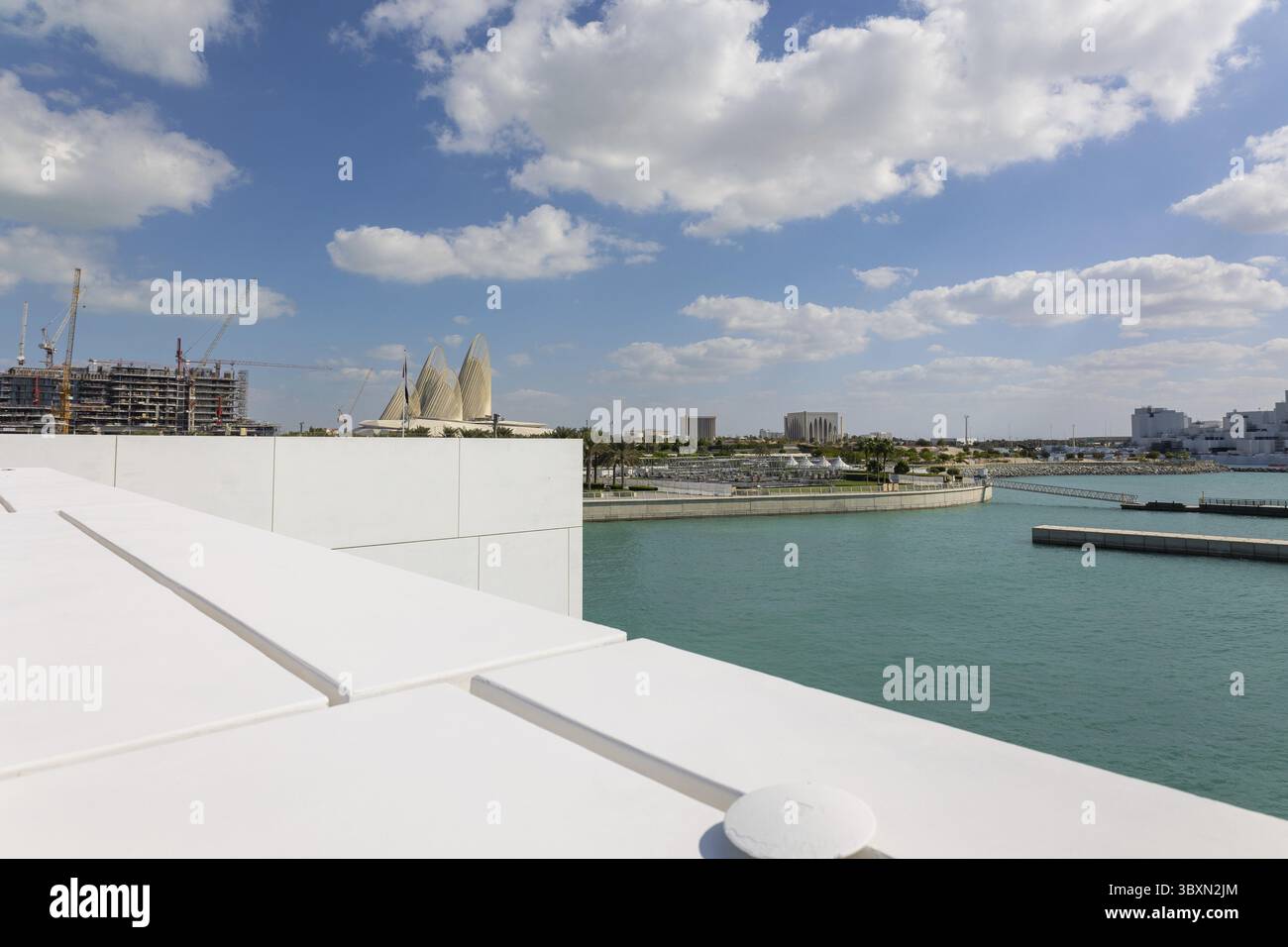 Blick auf die Stadt mit Türmen und Wolkenkratzern von Saadiyat Island in Abu Dhabi, Vereinigte Arabische Emirate. Blick von der Wasseroberfläche. Stockfoto