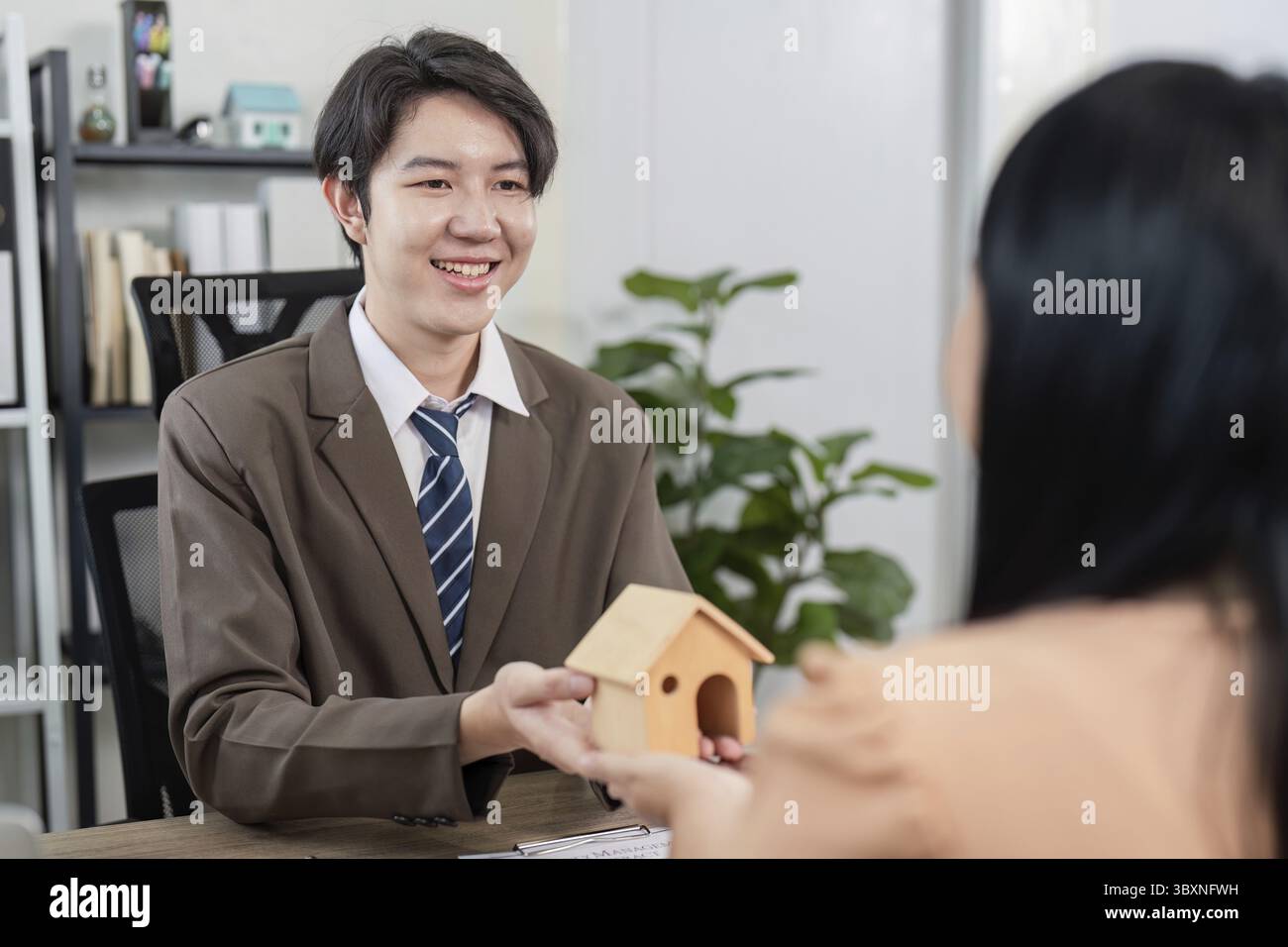 Ein Immobilienmakler leitet ein Gespräch mit einem Kunden über den Immobilienververkauf, wobei er sich darauf konzentriert, die Eigentumsziele des Kunden zu erreichen Stockfoto