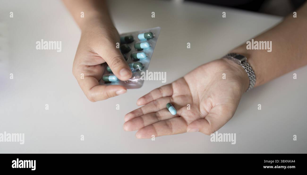 Nahaufnahme einer Frau, die die Pille mit Wasser in der Hand hält. Frauen nehmen Tablette von Kopfschmerzen, Schmerzmittel, Gesundheitswesen, Medizin, Behandlung. Therapiekonzept Stockfoto