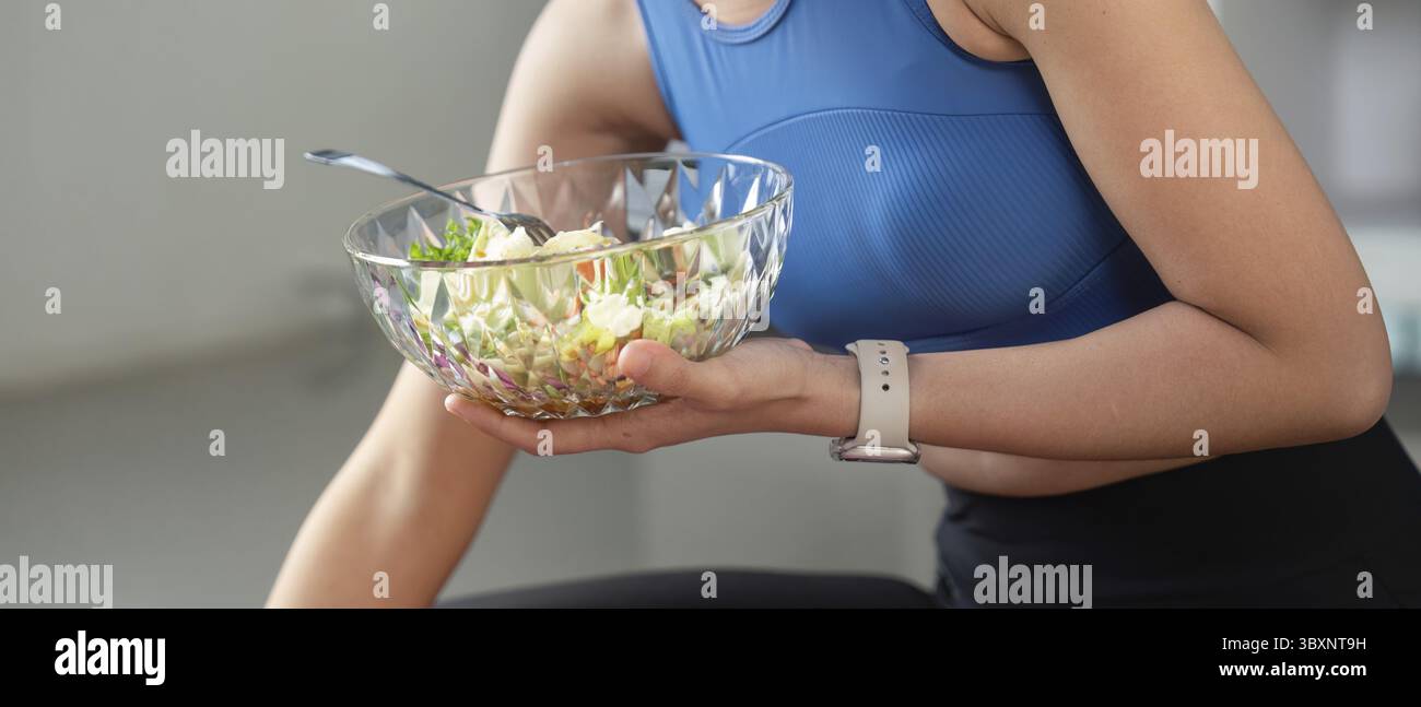 Fokussierte Frau, die einen nahrhaften Salat zubereitet, gesunde Essgewohnheiten und Lebensstil in einer modernen Umgebung präsentiert Stockfoto
