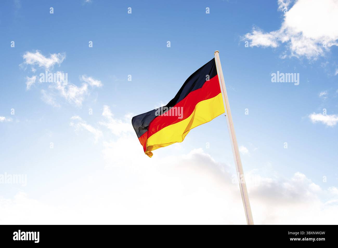 Eine deutsche Flagge mit schwarzen, roten und gelben Streifen vor Wolken in blauem Himmel Stockfoto