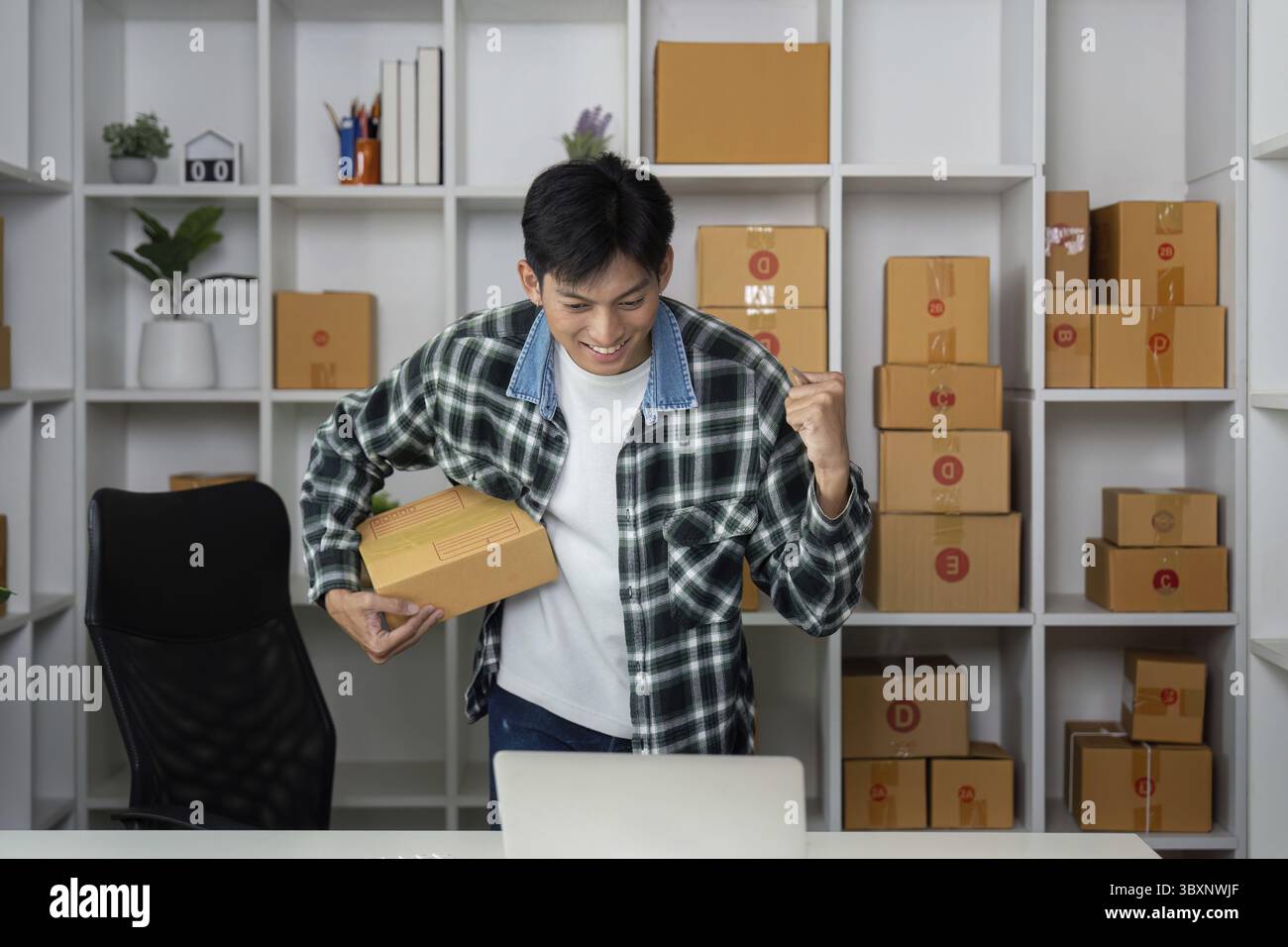 Ein begeisterter Unternehmer drückt sich vor Freude mit der Faust und feiert einen erfolgreichen Online-Verkauf an seinem gut organisierten Arbeitsplatz Stockfoto