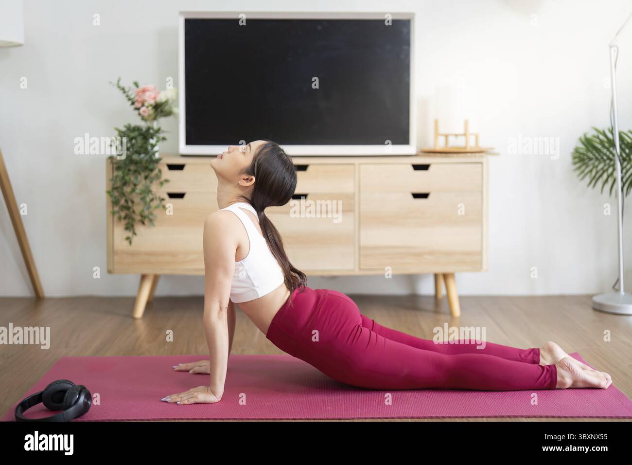 Dieses Bild zeigt eine Frau, die die nach oben gerichtete Hundestellung ausführt, die für den Aufbau der Kernkraft und die Verbesserung der Flexibilität zu Hause unerlässlich ist Stockfoto