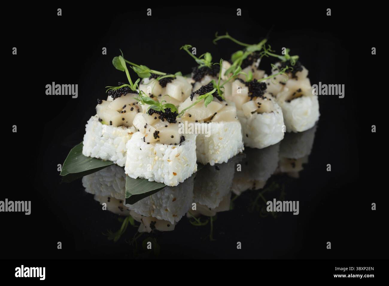 Traditionelle, köstliche, frische Sushi-Rolle auf schwarzem Hintergrund mit Spiegelung. Sushi-Rolle mit Reis, Nori, Frischkäse, Tobiko-Kaviar, Avocado. So Stockfoto