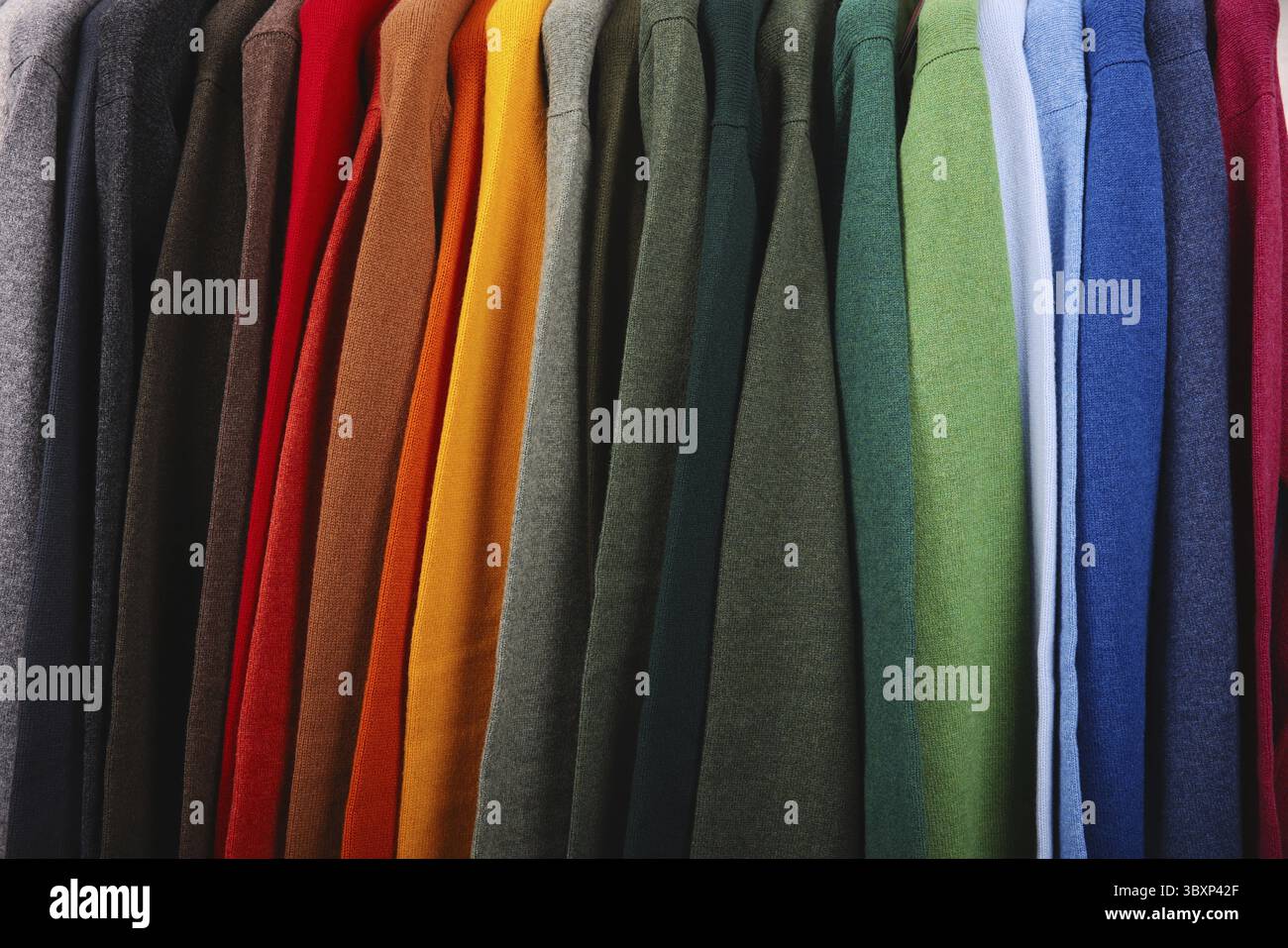 Warme Pullover. Herbst, Winterkleidung. Metallgestell mit verschiedenen Pullovern auf Kleiderbügeln in einer modernen Modeboutique. Leichtindustrie Stockfoto