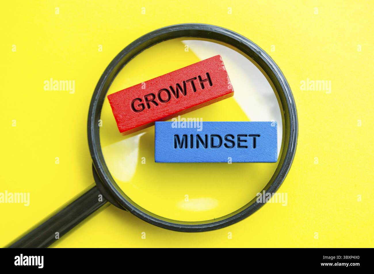 Text zur Wachstumseinstellung auf mehrfarbigen Holzblöcken mit Lupenuntergrund. Motivationskonzept Stockfoto
