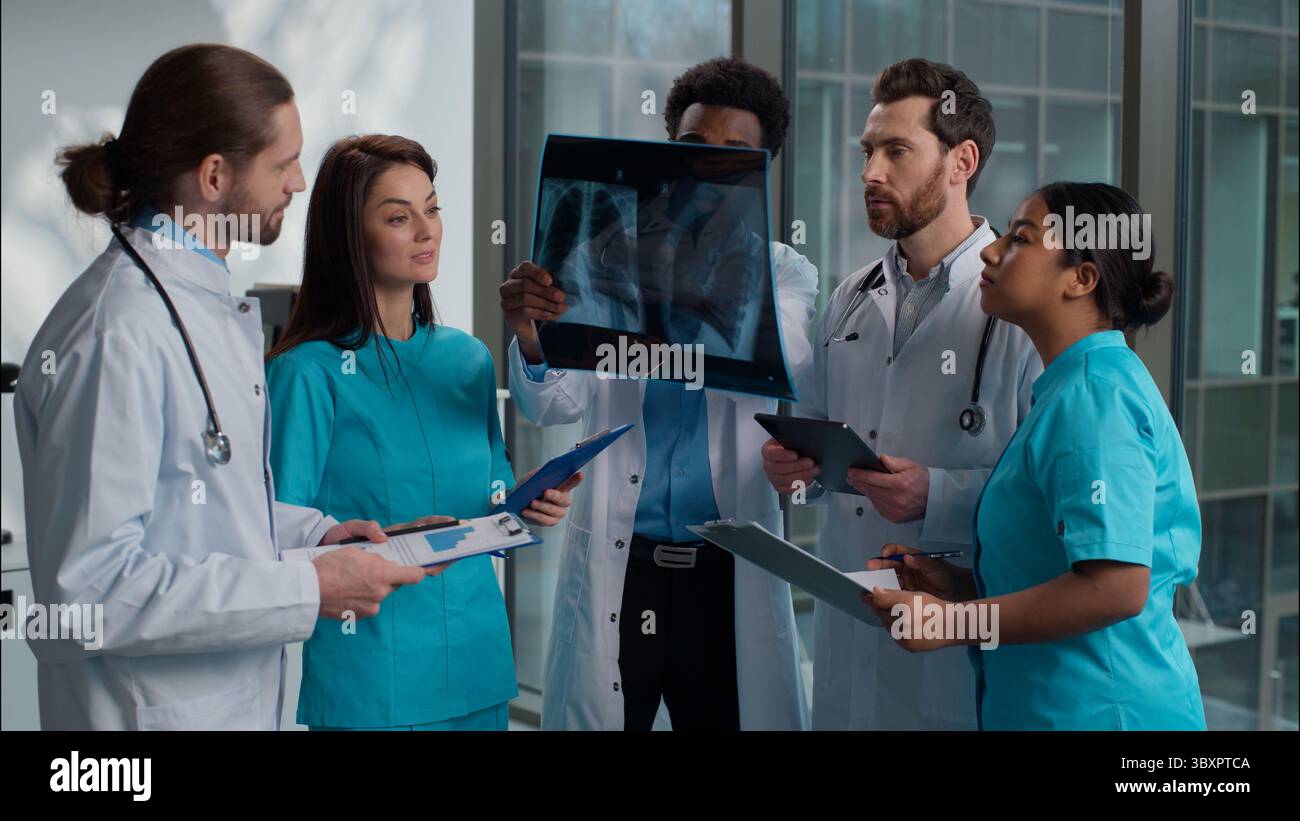 Gruppe von fünf multiethnischen Medizinstudenten Praktikanten Männer Frauen Ärzte Analyse der Röntgenergebnisse des Patienten mit digitalen Tablet Schreiben Clipboard Beratung Stockfoto